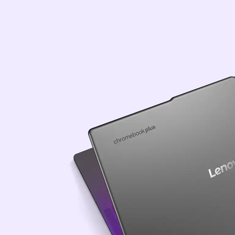 The back of a closed, dark gray Lenovo Chromebook Plus laptop is shown slightly open and at an angle against a white background.